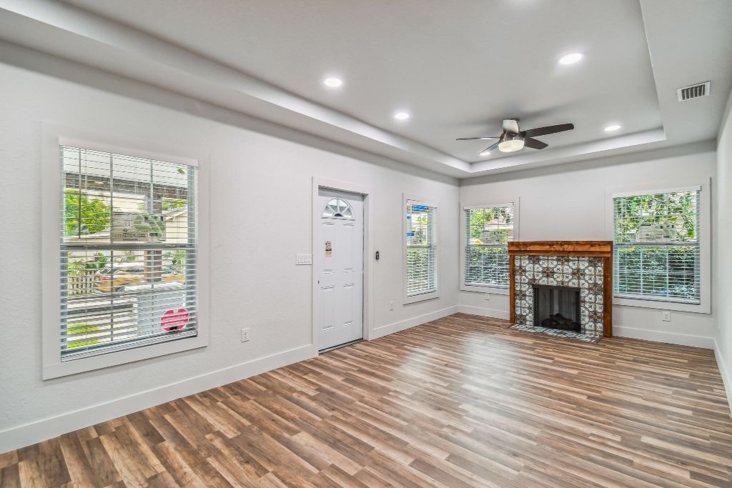 Baker Ave living room — bright open layout with tray ceiling, hardwood floors and encaustic fireplace