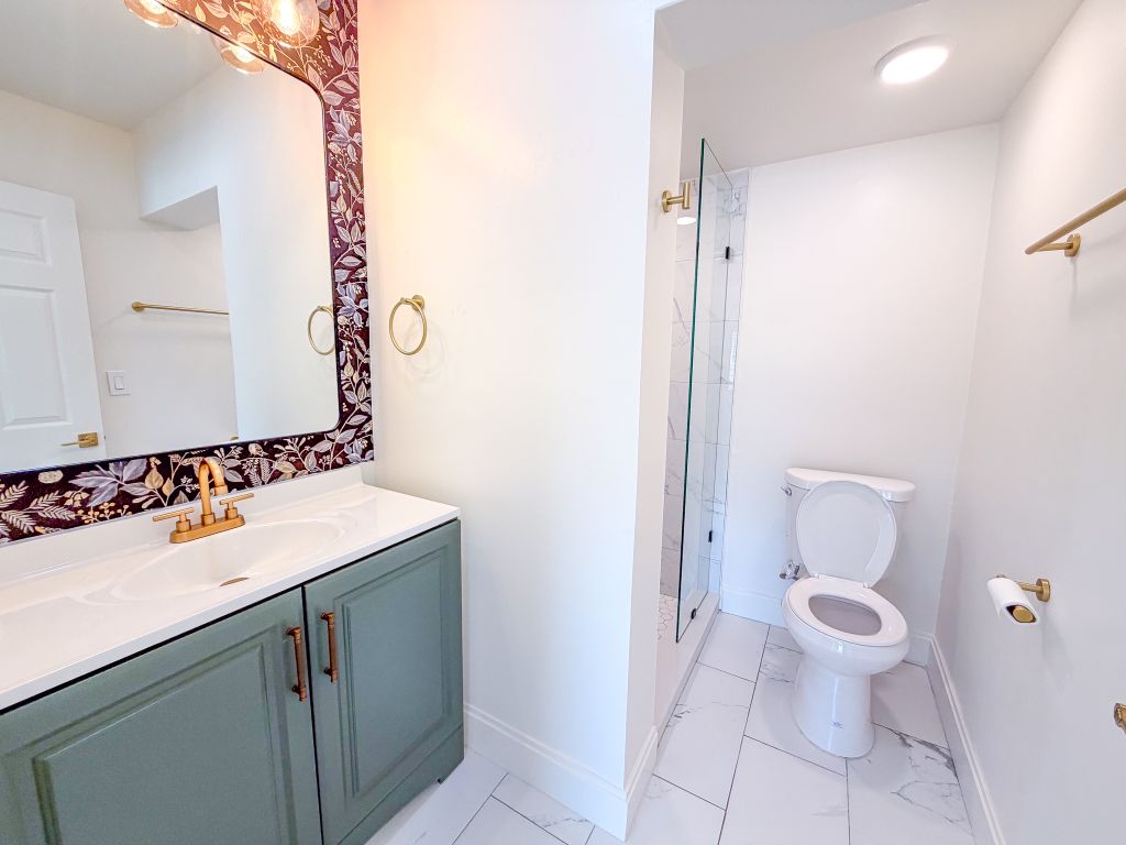 Renovation — green vanity with floral wallpaper and gold fixtures