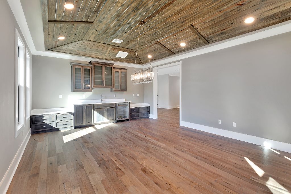Open concept living room with custom wet bar, reclaimed wood cathedral ceiling and statement chandelier